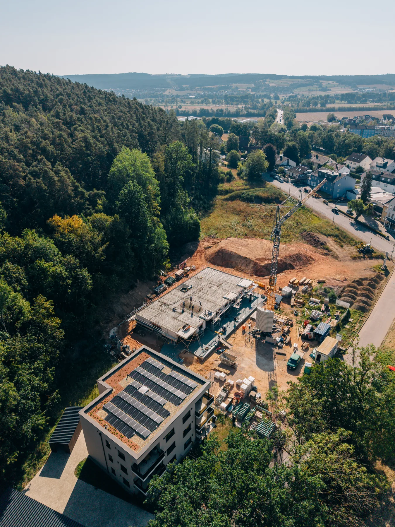 Luftbild der Baustelle am Waldrand mit Blick über Weiden